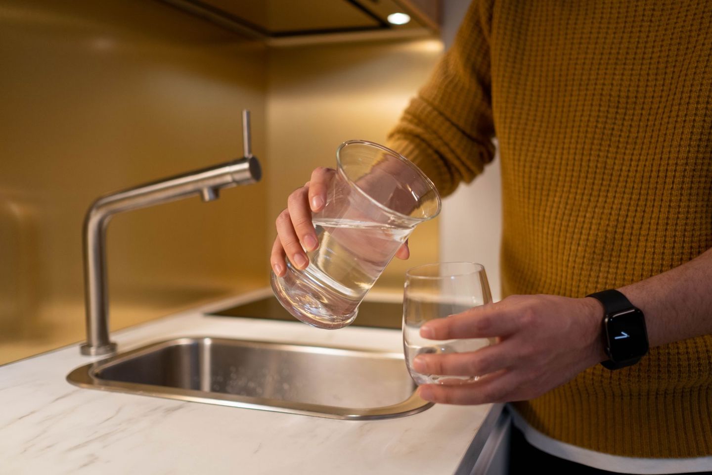 Person pouring water from a pitcher into a gl